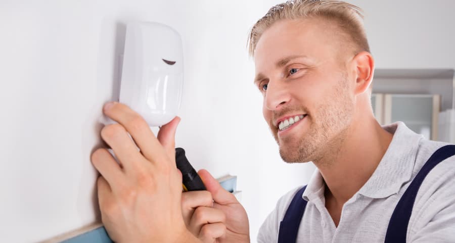 Man placing a motion detector on a wall